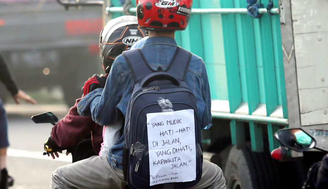 Pemudik sepeda motor menempelkan kertas berisi tulisan di bagian belakang motor saat melintasi jalur mudik Simpang Jomin, Karawang, Jawa Barat, Jumat (29/4). Tulisan tersebut berupa curhat mereka mengenai mudik. - JPNN.com