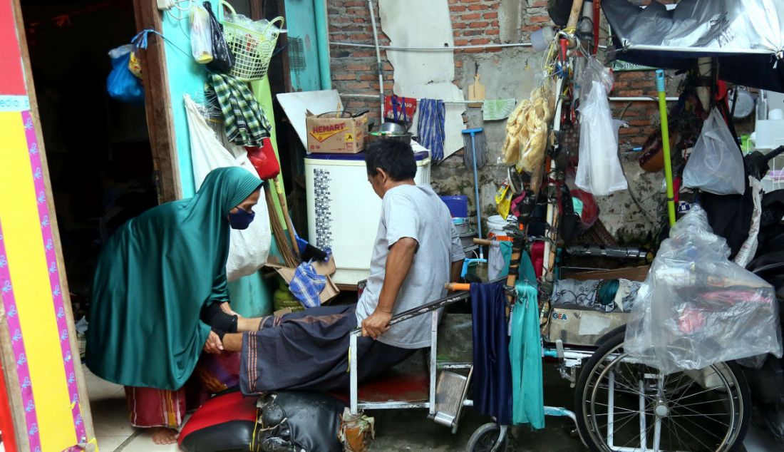 Penyandang disabilitas karena penyakit meningitis Kundiarto dibantu istrinya menaiki kursi roda di kawasan Cipete Utara, Kamis (2/6). - JPNN.com