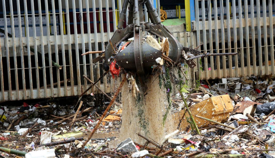 Alat berat mengangkut sampah di pintu air Manggarai, Jakarta, Sabtu (16/7). Hujan deras yang terjadi sejak Jumat (15/7) malam menyebabkan sampah terbawa dan memenuhi pintu air Manggarai. - JPNN.com