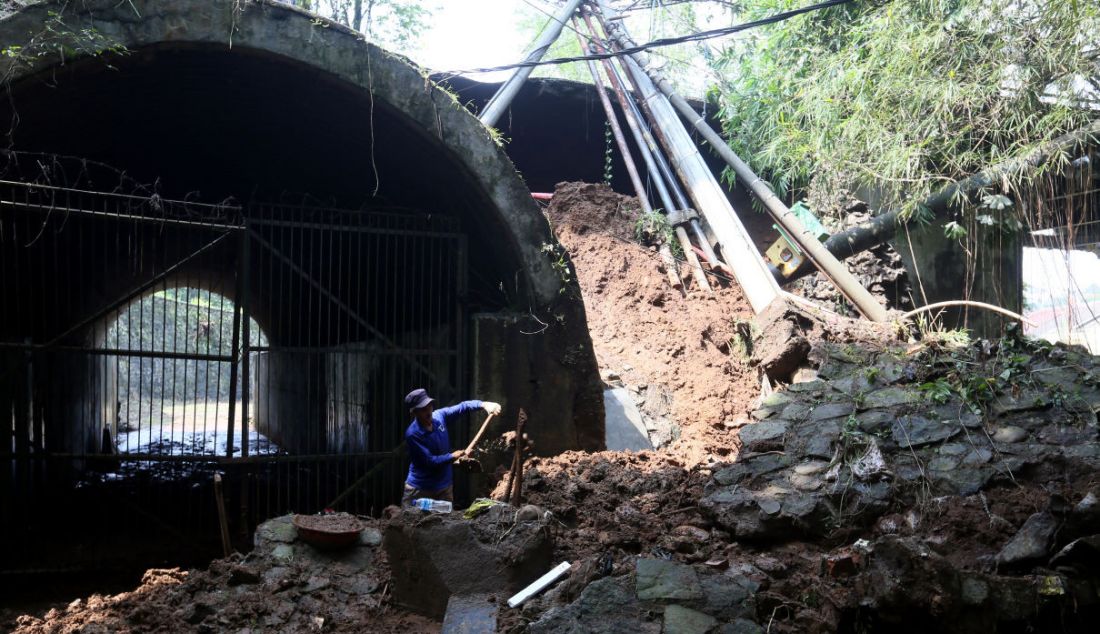Pekerja saat melakukan pembersihan tanah akibat longsor di ujung jembatan Cisadane Jalan Darul Quran yang mengalami longsor, Bogor, Jawa Barat, Rabu (12/10). Longsor tersebut diakibatkan hujan deras kemarin dan tidak mengalami korban jiwa. - JPNN.com