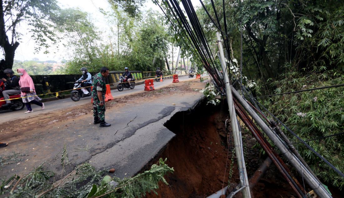 Seorang Babinsa melihat kondisi ujung jembatan Cisadane Jalan Darul Quran yang mengalami longsor, Bogor, Jawa Barat, Rabu (12/10). Longsor tersebut diakibatkan hujan deras kemarin dan tidak mengalami korban jiwa. - JPNN.com