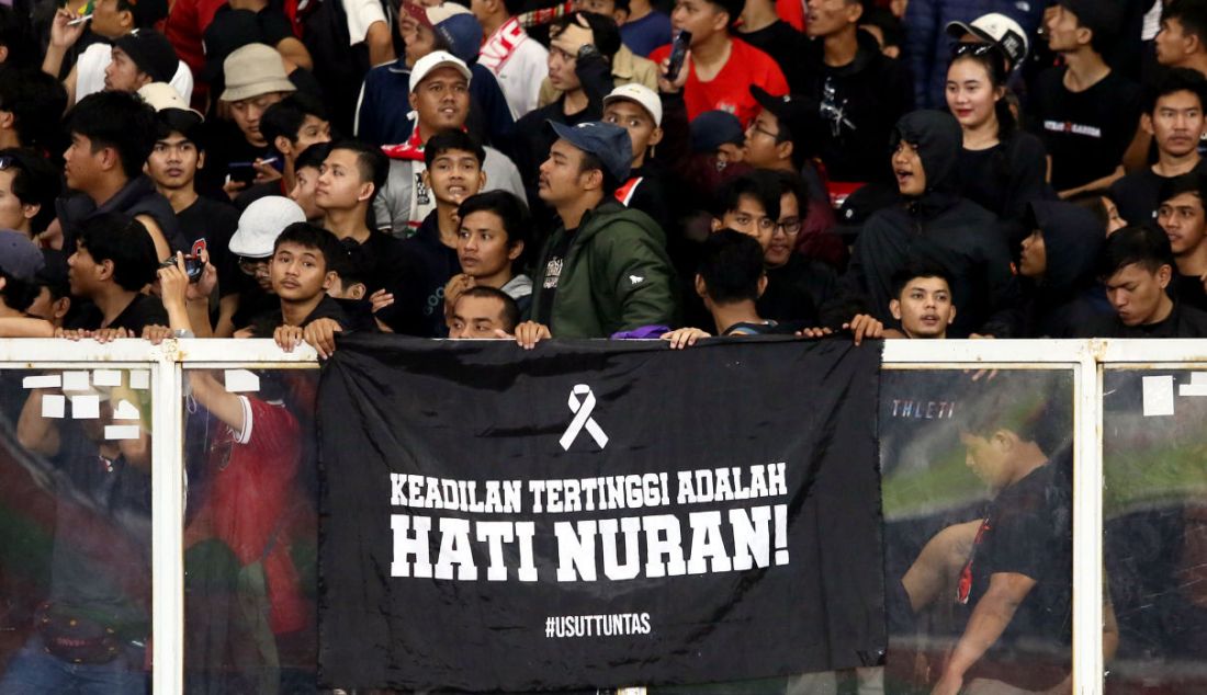 Suporter Timnas Indonesia membentangkan poster saat pertandingan lanjutan penyisihan Grup A Piala AFF 2022 Indonesia vs Thailand di Stadion Utama Gelora Bung Karno, Jakarta, Kamis (29/12). Aksi tersebut terkait tuntutan agar pemerintah mengusut tuntas Tragedi Kanjuruhan yang menelan korban 135 orang meninggal dan ratusan lainnya luka-luka. - JPNN.com