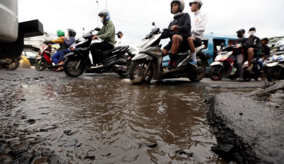Pengendara melintasi jalan rusak dan tergenang air di Jalan Raya Mayor Oking, Cibinong, Kabupaten Bogor, Jawa Barat, Selasa (3/1). - JPNN.com