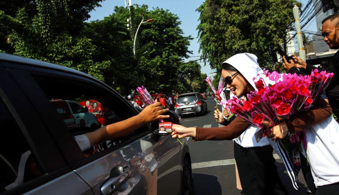 Sejumlah sukarelawan membagikan bunga mawar kepada pengendara, Jakarta, Sabtu (28/10). Kegiatan yang diselenggarakan oleh nakes yang terdiri dari dokter dan perawat ini dalam merayakan ulang tahun ke-55 Ganjar Pranowo sekaligus konsolidasi yang juga bentuk dukungan terhadap Ganjar Pranowo dan Mahfud MD sebagai bakal calon presiden dan bakal calon wakil presiden. - JPNN.com