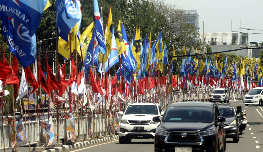 Pengendara lalu lintas melewati deretan alat peraga kampanye (APK) bendera partai dan caleg Pemilu 2024 di ruas Jl HOS Cokroaminoto, Menteng, Jakarta Pusat, Jumat (12/1). Selain mengganggu ketertiban umum, pemasangan APK yang tidak sesuai ini juga melanggar PKPU Nomor 15 Tahun 2023, tentang Kampanye Pemilu 2024. - JPNN.com