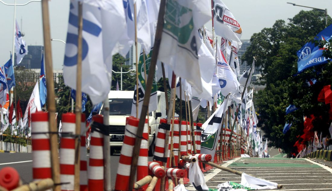 Pengendara lalu lintas melewati deretan alat peraga kampanye (APK) bendera partai dan caleg Pemilu 2024 di ruas Jl HOS Cokroaminoto, Menteng, Jakarta Pusat, Jumat (12/1). Selain mengganggu ketertiban umum, pemasangan APK yang tidak sesuai ini juga melanggar PKPU Nomor 15 Tahun 2023, tentang Kampanye Pemilu 2024. - JPNN.com