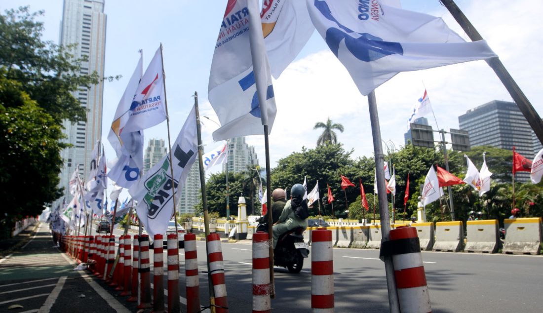 Pengendara lalu lintas melewati deretan alat peraga kampanye (APK) bendera partai dan caleg Pemilu 2024 di ruas Jl HOS Cokroaminoto, Menteng, Jakarta Pusat, Jumat (12/1). Selain mengganggu ketertiban umum, pemasangan APK yang tidak sesuai ini juga melanggar PKPU Nomor 15 Tahun 2023, tentang Kampanye Pemilu 2024. - JPNN.com