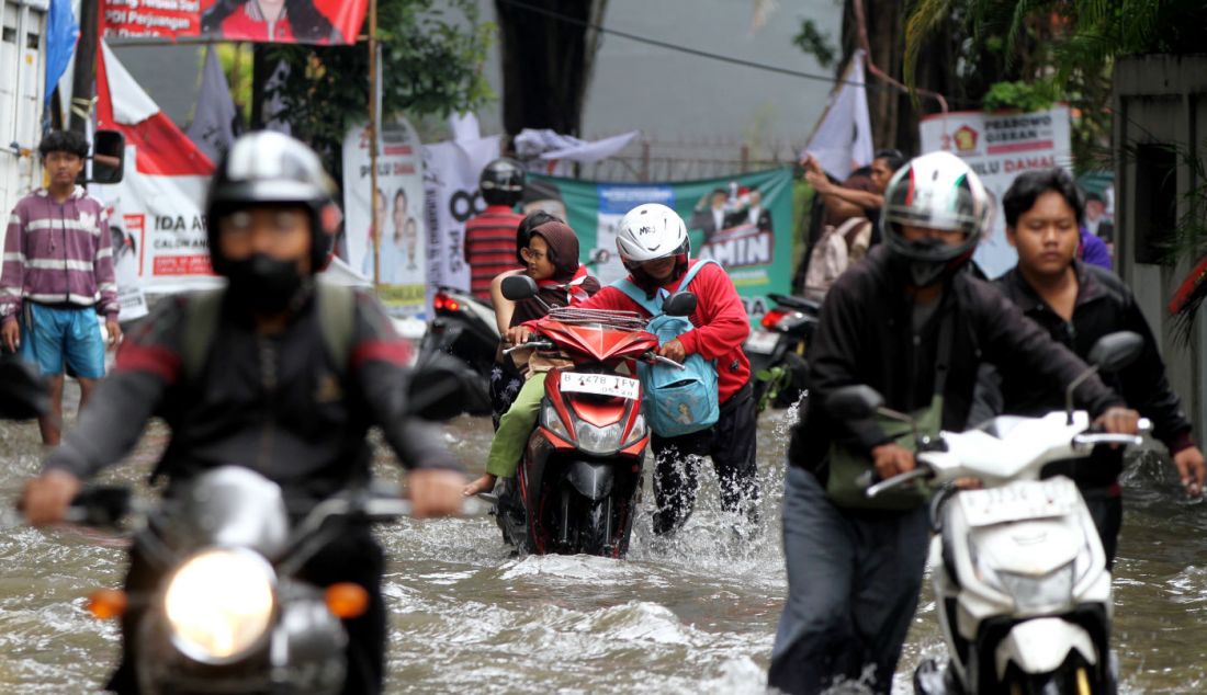 Pengendara mendorong motornya saat melintas di Jalan Pusdiklat Depnaker, Makasar, Jakarta Timur, Rabu (31/1). Hujan deras yang melanda Jakarta sejak Rabu malam (31/1) menyebabkan Jalan Pusdiklat Depnaker, Kecamatan Makasar Jakarta Timur terendam banjir. - JPNN.com