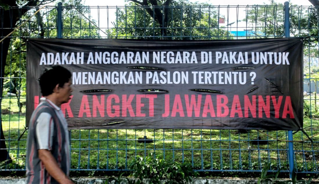 Warga melintas di depan spanduk bertuliskan Hak Angket Jawabannya, Jakarta, Jumat (1/3). - JPNN.com