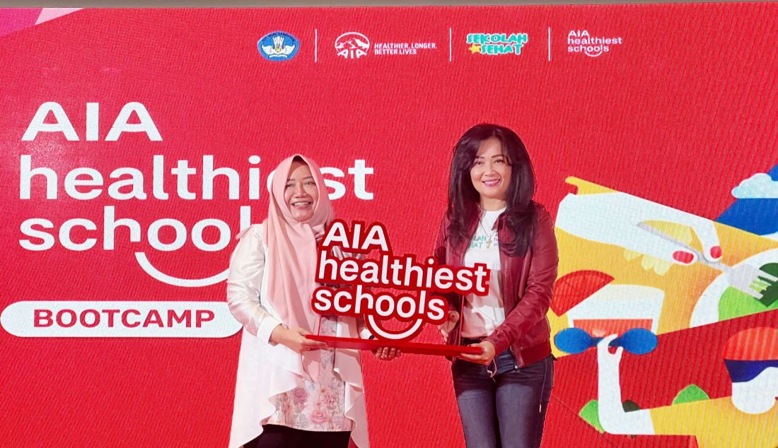 Direktur Hukum dan Kepatuhan AIA Rista Qatrini Manurung (kanan) menyerahkan pelakat kepada Direktur Sekolah Menengah Pertama Maulani Mega Hapsari seusai membuka Program AIA Healthiest Schools (AHS) Bootcamp, Jakarta, Senin (10/2). Kegiatan ini dirancang untuk membantu sekolah-sekolah peserta kompetisi AHS dalam merancang dan mengeksekusi proyek sekolah sehat yang nantinya akan mereka serahkan sebelum tenggat waktu pada 8 Maret 2025 melalui kanal aia.id/AHS. AHS yang berfokus pada empat pilar utama: Makan Sehat, Gaya Hidup Aktif, Kesehatan Mental, dan Sehat & Lestari ini sejalan dengan komitmen AIA untuk membantu jutaan keluarga di Indonesia hidup lebih sehat, lebih lama, lebih baik, AIA berupaya untuk menciptakan lingkungan sekolah yang lebih sehat dan inovatif. Para peserta akan diberikan akses gratis ke modul pembelajaran interaktif dan berkesempatan mengikuti kompetisi ide sekolah sehat dengan total hadiah mencapai US$100,000 dalam bentuk fasilitas dan sarana pendukung pendidikan. - JPNN.com