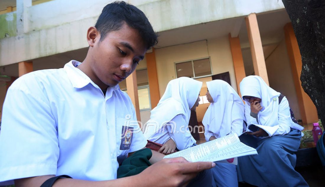 Siswa mempersiapkan materi ujian sambil menunggu giliran Ujian Nasional Berbasis Kompuer (UNBK) hari pertama di SMA N I Tajur Halang, Kabupaten Bogor, Jawa Barat, Senin (10/4). - JPNN.com