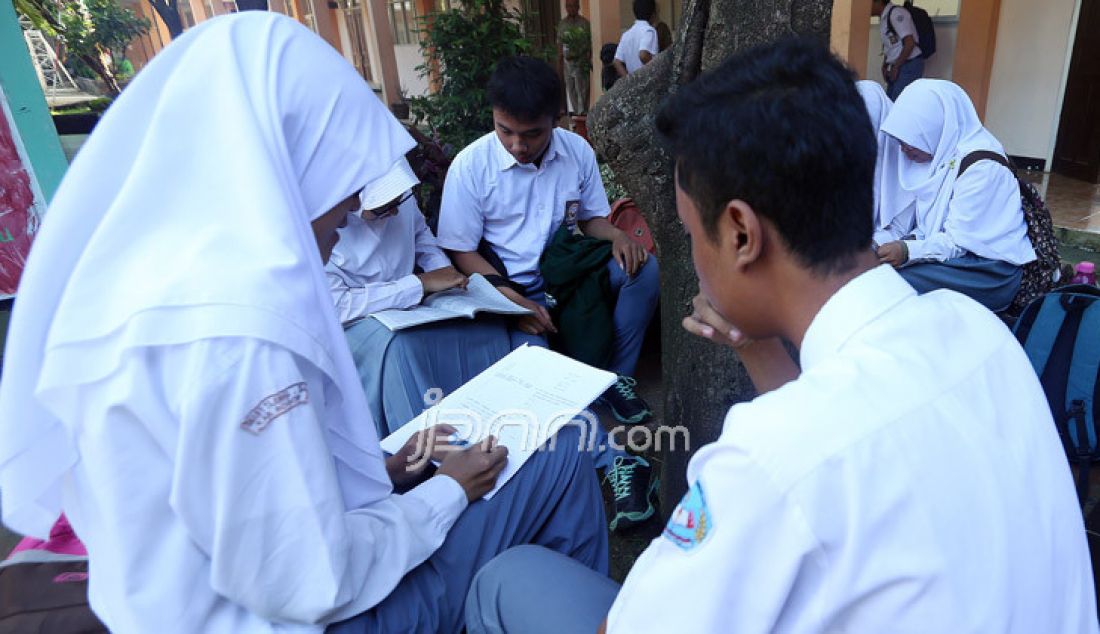 Siswa mempersiapkan materi ujian sambil menunggu giliran Ujian Nasional Berbasis Kompuer (UNBK) hari pertama di SMA N I Tajur Halang, Kabupaten Bogor, Jawa Barat, Senin (10/4). - JPNN.com