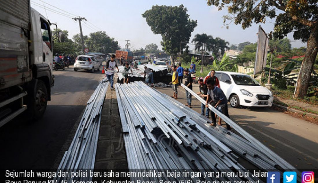 Sejumlah warga dan polisi berusaha memindahkan baja ringan yang menutupi Jalan Raya Parung KM 45, Kemang, Kabupaten Bogor, Senin (5/6). Baja ringan tersebut berasal dari truk yang terguling akibat kelebihan muatan. - JPNN.com