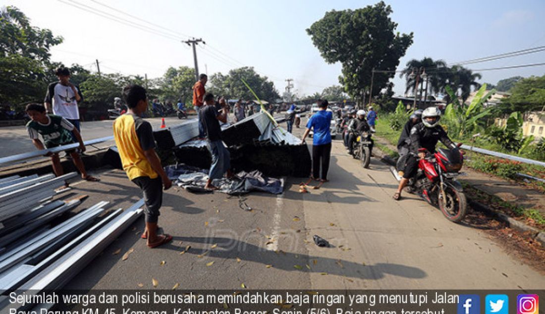 Sejumlah warga dan polisi berusaha memindahkan baja ringan yang menutupi Jalan Raya Parung KM 45, Kemang, Kabupaten Bogor, Senin (5/6). Baja ringan tersebut berasal dari truk yang terguling akibat kelebihan muatan. - JPNN.com