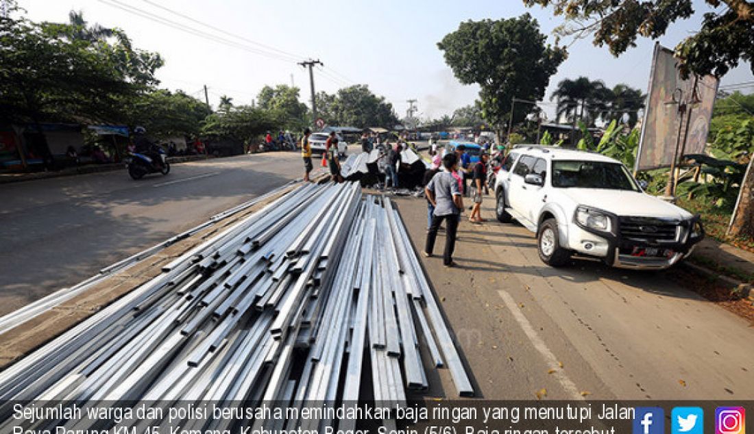 Sejumlah warga dan polisi berusaha memindahkan baja ringan yang menutupi Jalan Raya Parung KM 45, Kemang, Kabupaten Bogor, Senin (5/6). Baja ringan tersebut berasal dari truk yang terguling akibat kelebihan muatan. - JPNN.com