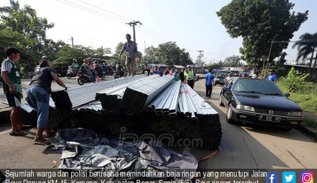 Sejumlah warga dan polisi berusaha memindahkan baja ringan yang menutupi Jalan Raya Parung KM 45, Kemang, Kabupaten Bogor, Senin (5/6). Baja ringan tersebut berasal dari truk yang terguling akibat kelebihan muatan. - JPNN.com