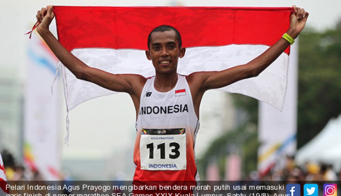 Pelari Indonesia Agus Prayogo mengibarkan bendera merah putih usai memasuki garis finish di nomor marathon SEA Games XXIX Kuala Lumpur, Sabtu (19/8). Agus meraih medali perak dengan catatan waktu dua jam 27 menit 16 detik. - JPNN.com