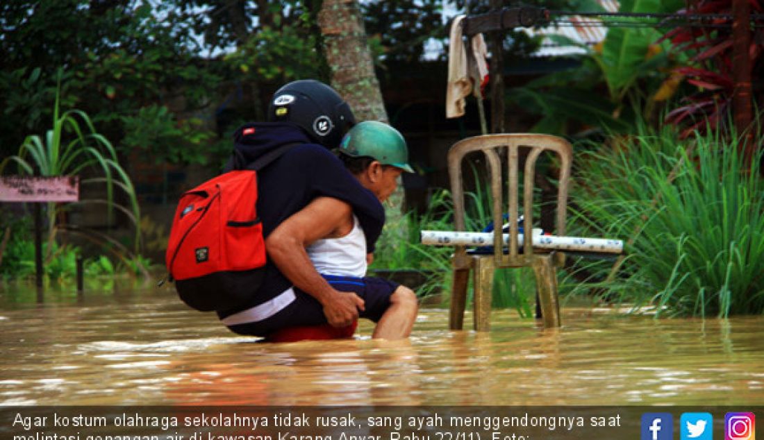 Agar kostum olahraga sekolahnya tidak rusak, sang ayah menggendongnya saat melintasi genangan air di kawasan Karang Anyar, Rabu 22/11). - JPNN.com