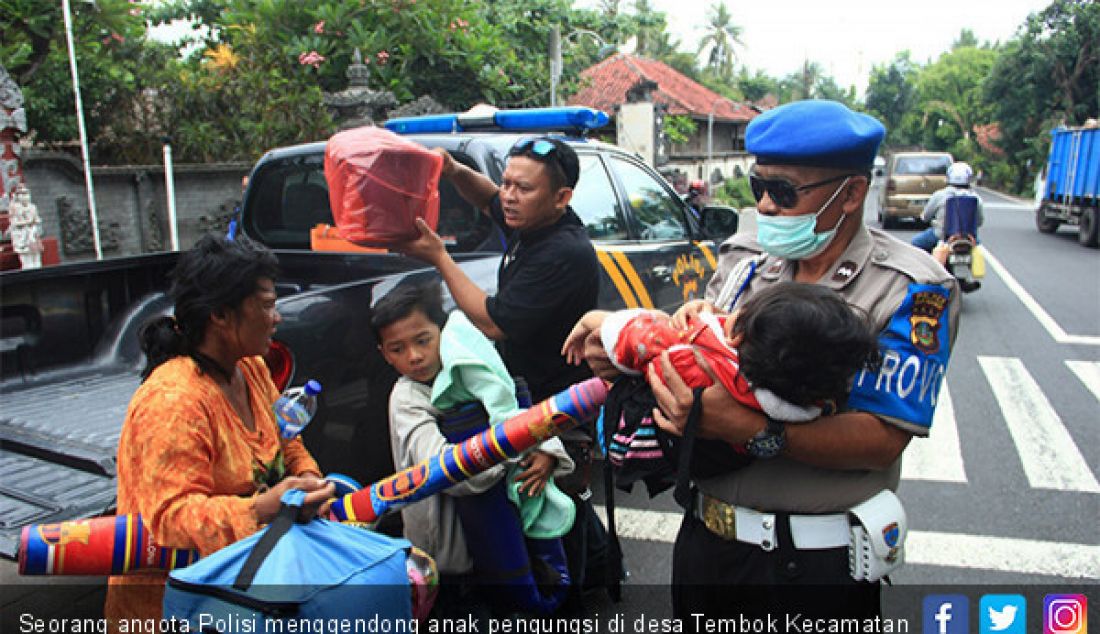 Seorang angota Polisi menggendong anak pengungsi di desa Tembok Kecamatan Tejakula Buleleng, Bali. - JPNN.com