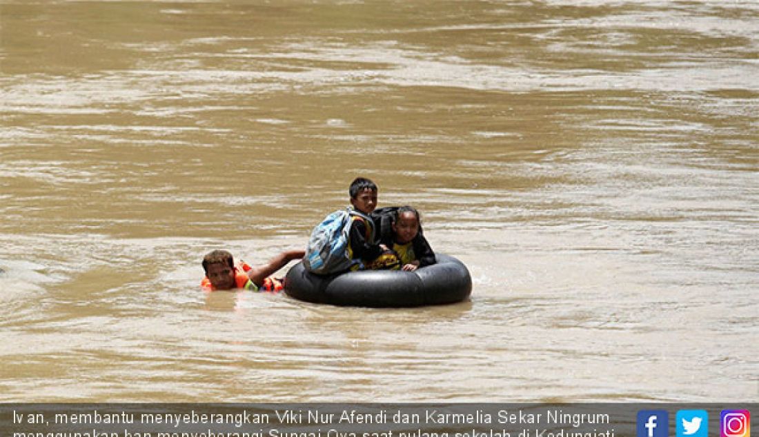 Ivan, membantu menyeberangkan Viki Nur Afendi dan Karmelia Sekar Ningrum menggunakan ban menyeberangi Sungai Oya saat pulang sekolah di Kedungjati, Selopamioro, Imogiri, Bantul, DIJ, Jumat (9/2). - JPNN.com