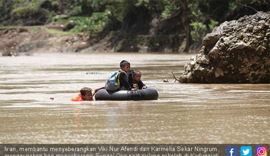 Ivan, membantu menyeberangkan Viki Nur Afendi dan Karmelia Sekar Ningrum menggunakan ban menyeberangi Sungai Oya saat pulang sekolah di Kedungjati, Selopamioro, Imogiri, Bantul, DIJ, Jumat (9/2). - JPNN.com