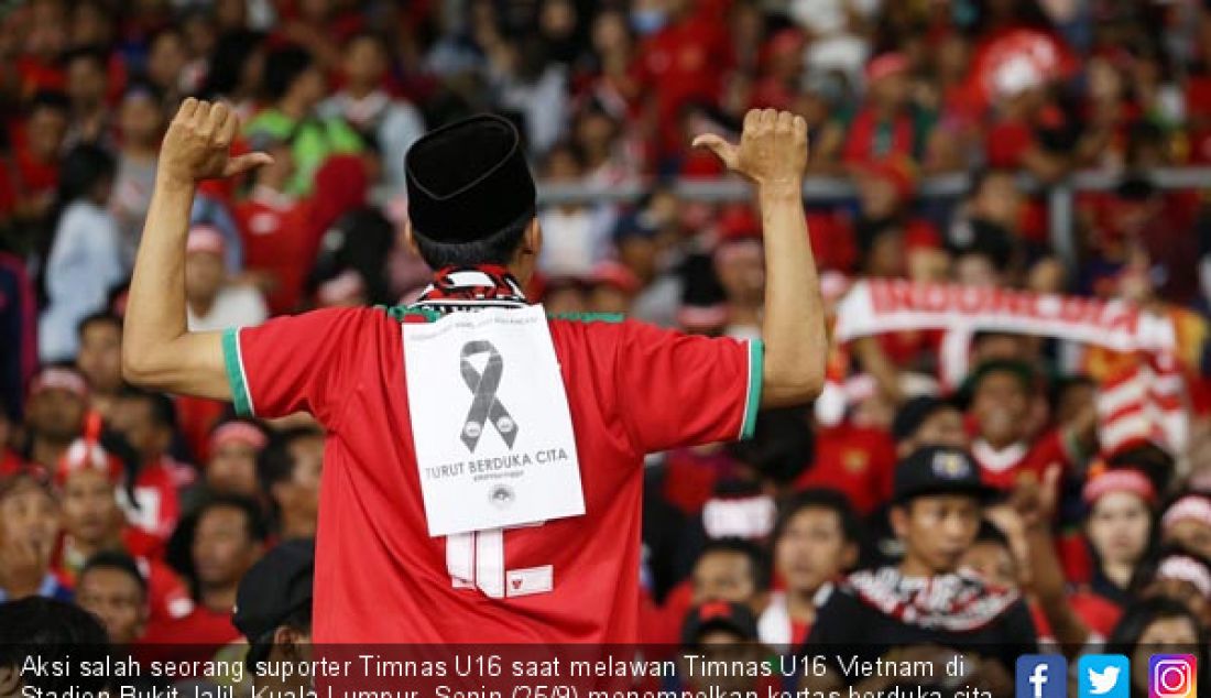 Aksi salah seorang suporter Timnas U16 saat melawan Timnas U16 Vietnam di Stadion Bukit Jalil, Kuala Lumpur, Senin (25/9) menempelkan kertas berduka cita mengenang suporter Persija yang tewas. - JPNN.com