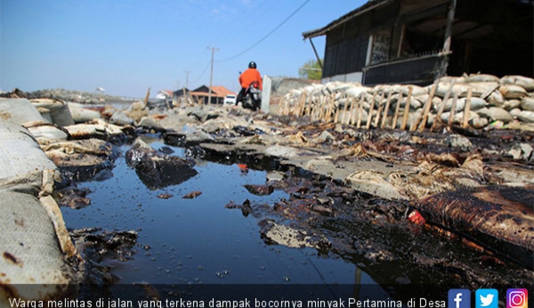 Warga melintas di jalan yang terkena dampak bocornya minyak Pertamina di Desa Pisangan, Cibuaya, Kab. Karawang, Selasa (23/7). - JPNN.com