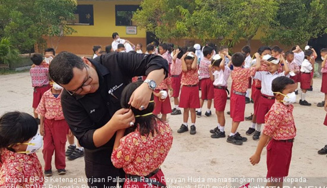 Kepala BPJS Ketenagakerjaan Palangka Raya, Royyan Huda memasangkan masker kepada siswa SDN 5 Palangka Raya, Jumat (6/9). Total sebanyak 1500 masker dibagikan kepada siswa dan warga. - JPNN.com