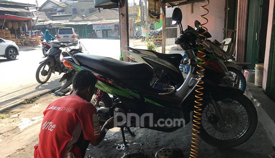 Mekanik melakukan perbaikan sekaligus perawatan sepeda motor pelanggan di bengkel miliknya, kota Ciledug, Tangerang, Selasa (10/9). - JPNN.com