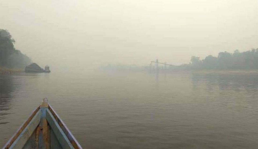 Sebuah perahu berlayar di Sungai Barito di wilayah Barito Utara yang tertutup kabut asap tebal, Jumat (13/9) pagi. Pemerintah kabupaten (Pemkab) Barito Utara meliburkan Paud - SLTP. - JPNN.com