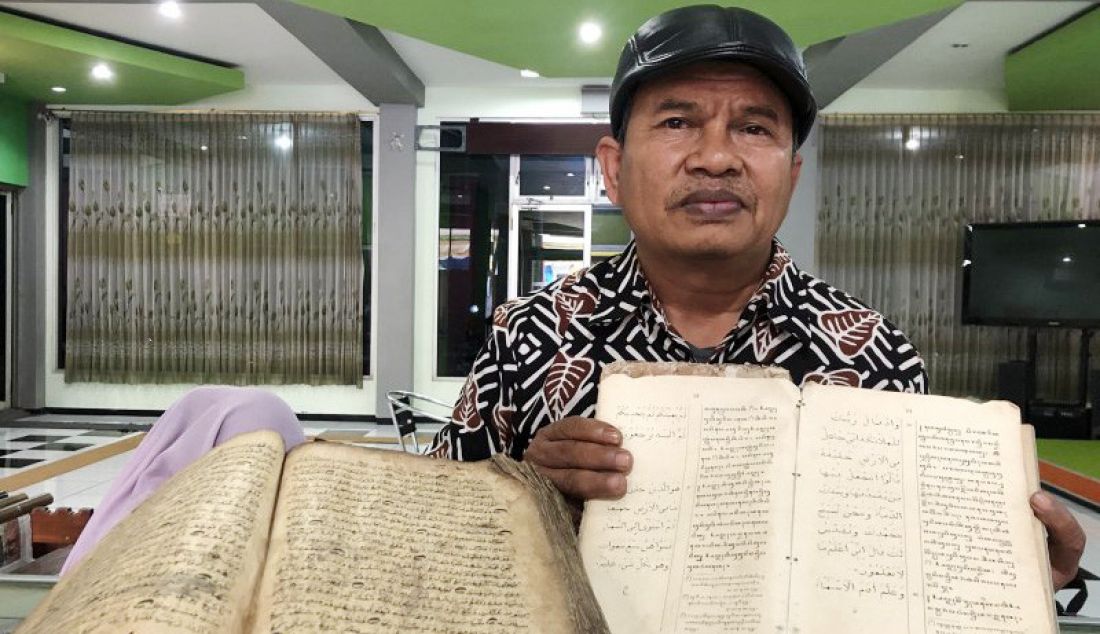 Lulut Edi Santoso, menunjukkan beberapa koleksi manuskrip kuno yang dipamerkan di Perpustakaan Umum dan Arsip Daerah Kota Malang, Jawa Timur, Kamis (19/9). Setidaknya terdapat puluhan manuskrip dipajang. - JPNN.com