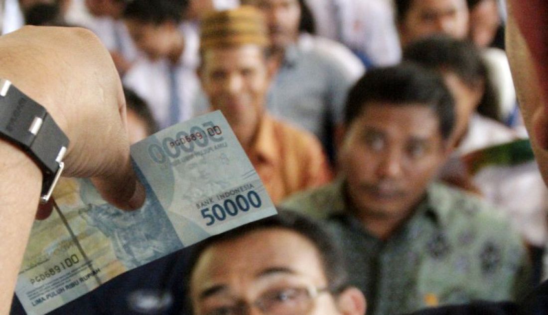 Warga memperhatikan uang rupiah senilai Rp50 ribu ketika Bank Indonesia mensosialisasikan ciri-ciri keaslian Rupiah di desa Nggorang, Kabupaten Manggarai Barat, NTT. - JPNN.com