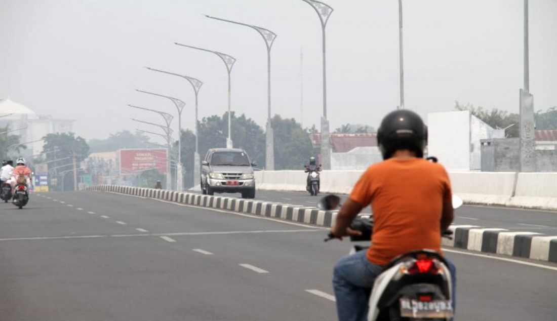 Seorang pengendara motor melintasi kawasan jalan layang simpang Surayaba di Banda Aceh, Selasa (24/9). Perlahan kabut asap yang meliputi kawasan di Aceh mulai berkurang. - JPNN.com