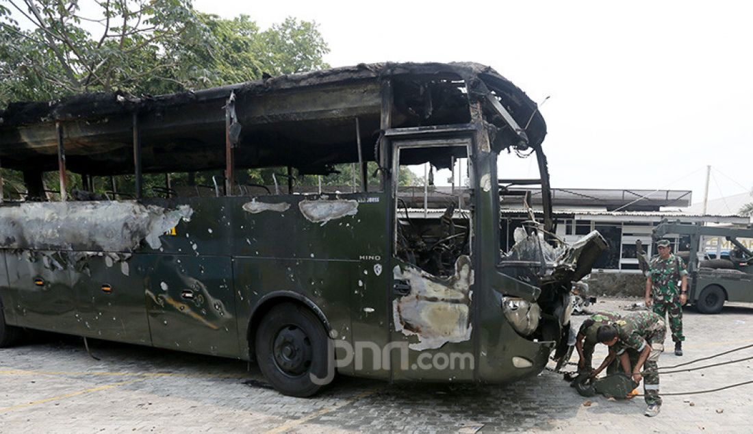 Petugas saat mengevakuasi bangkai bus milik TNI yang dibakar massa pasca bentrok antara mahasiswa dengan petugas keamanan di Lapangan Tembak, Jakarta, Rabu (25/9). - JPNN.com