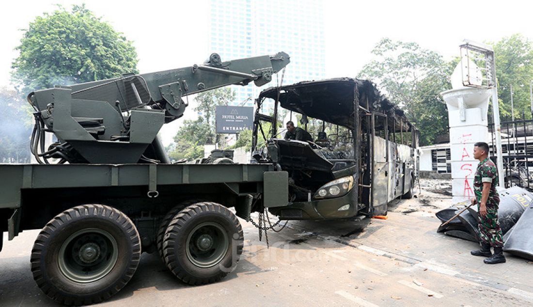 Petugas saat mengevakuasi bangkai bus milik TNI yang dibakar massa pasca bentrok antara mahasiswa dengan petugas keamanan di Lapangan Tembak, Jakarta, Rabu (25/9). - JPNN.com