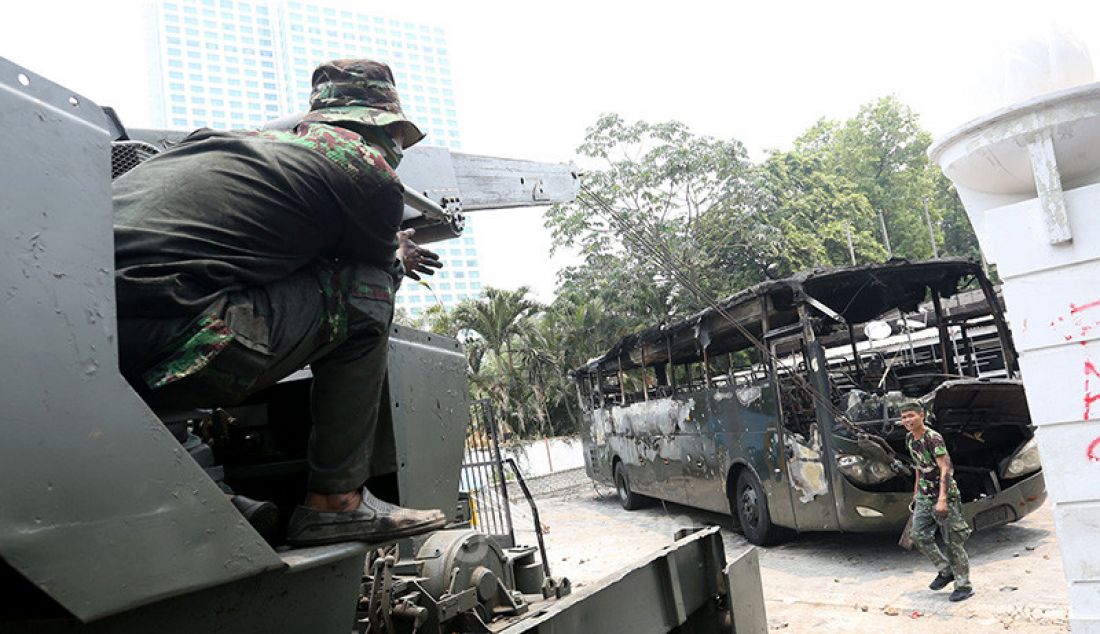 Petugas saat mengevakuasi bangkai bus milik TNI yang dibakar massa pasca bentrok antara mahasiswa dengan petugas keamanan di Lapangan Tembak, Jakarta, Rabu (25/9). - JPNN.com