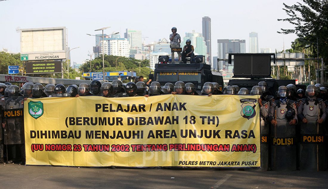 Petugas kepolisian membentangkan spanduk himbauan kepada pelajar di Kawasan gedung DPR, Jakarta, Senin (30/9). - JPNN.com