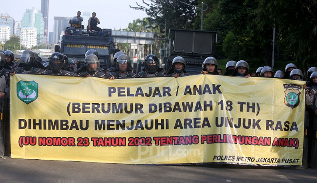 Petugas kepolisian membentangkan spanduk himbauan kepada pelajar di Kawasan gedung DPR, Jakarta, Senin (30/9). - JPNN.com