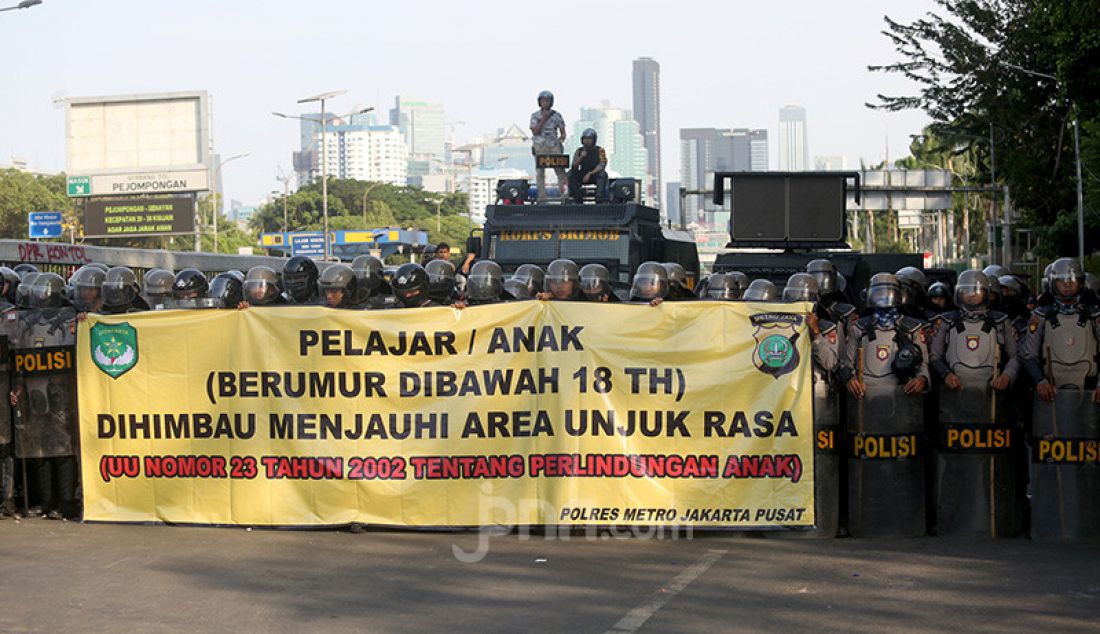 Petugas kepolisian membentangkan spanduk himbauan kepada pelajar di Kawasan gedung DPR, Jakarta, Senin (30/9). - JPNN.com