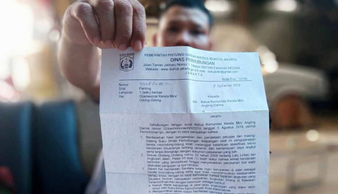 Sekretaris komunitas Angkutan Lingkungan Darma Wisata (Anglingdarma), Muhammad Yasin, memperlihatkan surat sosialisasi dari Suku Dinas Perhubungan Jakarta Timur perihal rencana larangan operasional odong-odong, Jumat (25/10). - JPNN.com