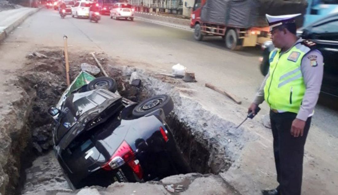 Mobil pribadi jenis minibus terperosok lubang galian utilitas di Jalan DI Panjaitan Jakarta Timur, Senin (25/11). Polisi memastikan tidak ada korban jiwa dalam kejadian itu. - JPNN.com