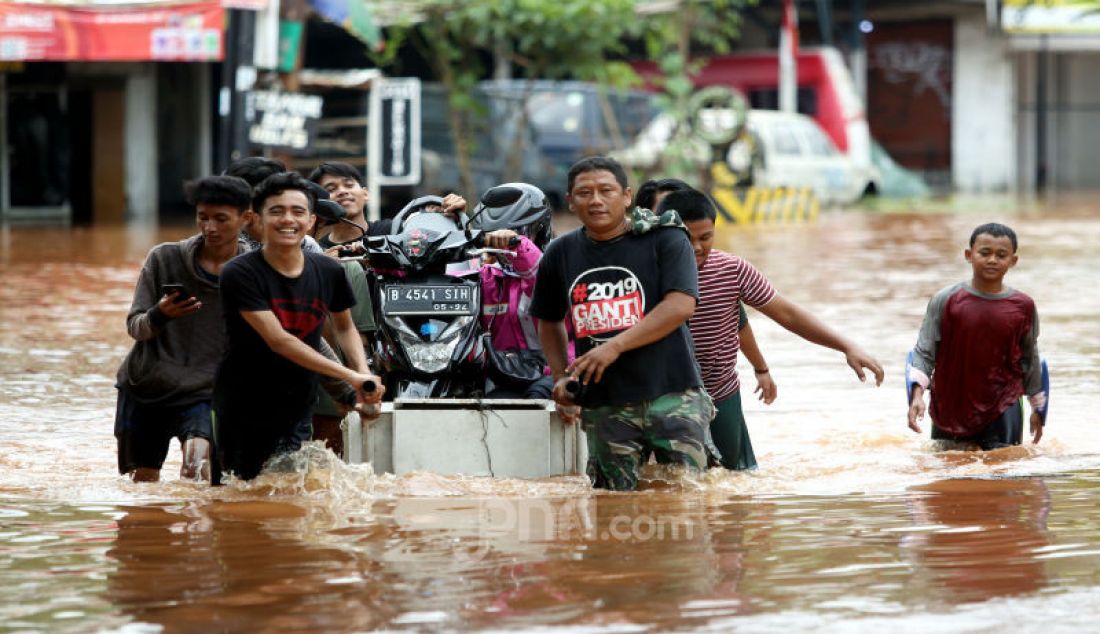 Warga mengangkut sepada motor saat melintasi banjir yang merendam di Raya Pondok Cabe, Tangsel, Rabu (1/1). Banjir tersebut memutus akses jalan Raya Pondok Cabe. - JPNN.com