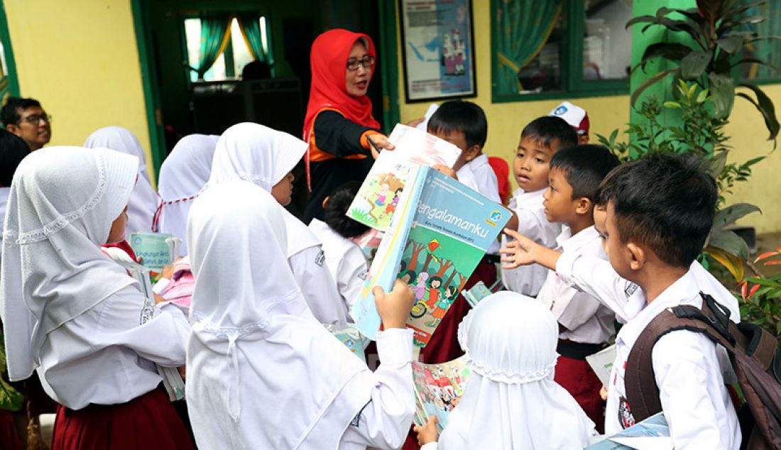 Sejumlah guru membagikan buku bacaan dan peralatan tulis siswa-siswi yang merupakan bantuan dari Mendikbud di SDN Cirimekar 2, Cibinong, Bogor, Selasa (6/1). - JPNN.com