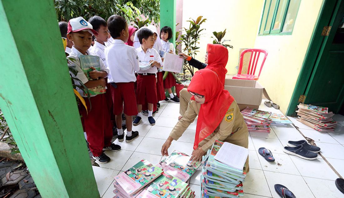 Sejumlah guru membagikan buku bacaan dan peralatan tulis siswa-siswi yang merupakan bantuan dari Mendikbud di SDN Cirimekar 2, Cibinong, Bogor, Selasa (6/1). - JPNN.com