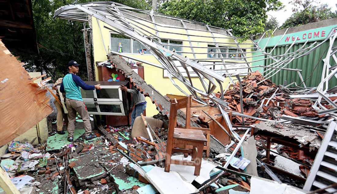 Guru dan pegawai sekolah memindahkan lemari dari reruntuhan atas kelas yang roboh di SDN Cirimekar 2, Cibinong, Bogor, Selasa (6/1). Bangunan sekolah roboh usai diterpa hujan deras. - JPNN.com