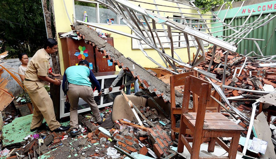 Guru dan pegawai sekolah memindahkan lemari dari reruntuhan atas kelas yang roboh di SDN Cirimekar 2, Cibinong, Bogor, Selasa (6/1). Bangunan sekolah roboh usai diterpa hujan deras. - JPNN.com