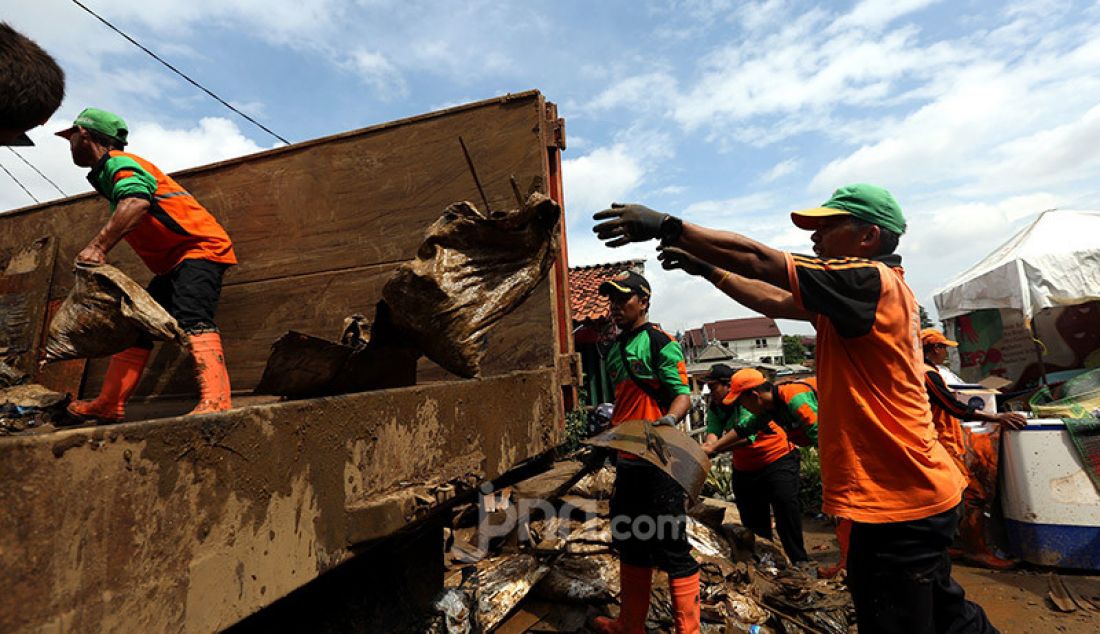 Petugas PPSU membersihkan puing-puing dan lumpur akibat banjir di Kelurahan Pengadegan, Jakarta, Selasa (7/1). Daerah tersebut masih terlihat genangan air bercampur lumpur. - JPNN.com