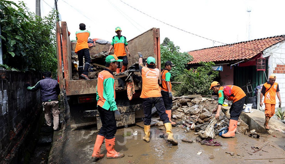 Petugas PPSU membersihkan puing-puing dan lumpur akibat banjir di Kelurahan Pengadegan, Jakarta, Selasa (7/1). Daerah tersebut masih terlihat genangan air bercampur lumpur. - JPNN.com