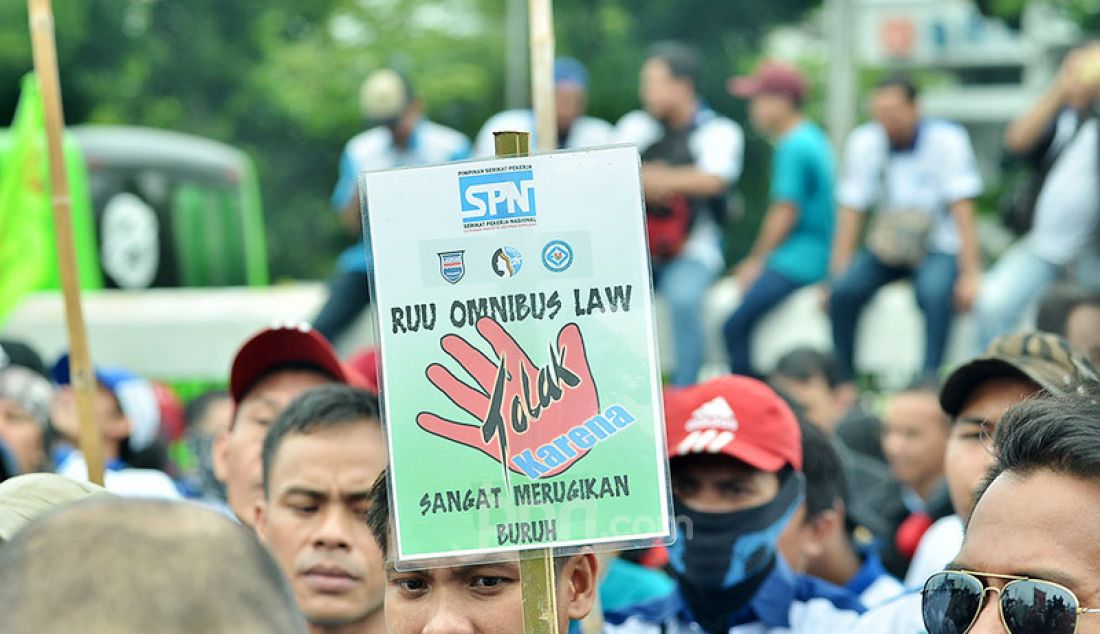 Seorang buruh membawa poster penolakan terhadap Omnibus Law, saat aksi demonstrasi di depan Gedung Parlemen, Senayan, Jakarta, Senin (20/1). - JPNN.com