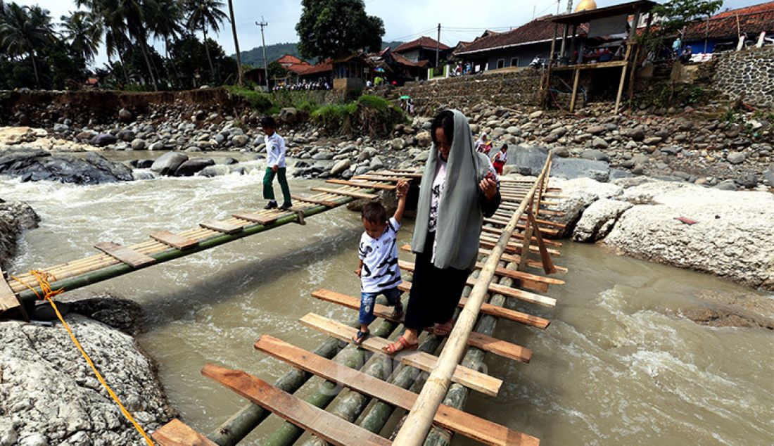 Warga dan pelajar melewati jembatan darurat di Sungai Cidurian, Desa Sukamaju, Cigudeg, Bogor, Jawa Barat, Rabu (5/2). Jembatan penghubung kampung Nanggung, Ciasahan, Cikaret dan Cigowong ambruk diterjang banjir bandang. - JPNN.com